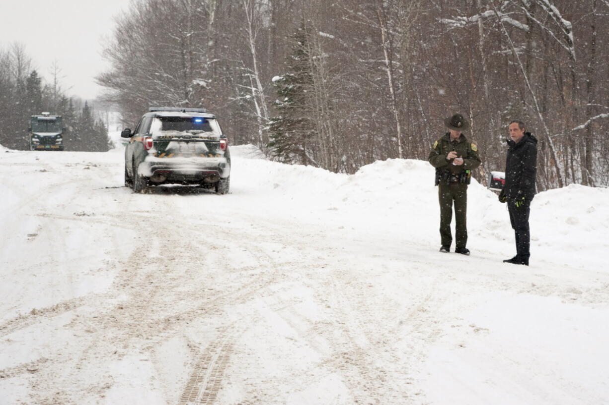 FILE -- A Vermont State Trooper, center, speaks to a homeowner, Thursday, Jan. 8, 2018, near an area on Peacham Road, in Barnet, Vt., where the body of Gregory Davis was found. Los Angeles biotech investor Serhat Gumrukcu pleaded not guilty Tuesday, Oct. 4, 2022, in a transcontinental murder-for-hire conspiracy that led to the 2018 abduction and killing of Gregory Davis.