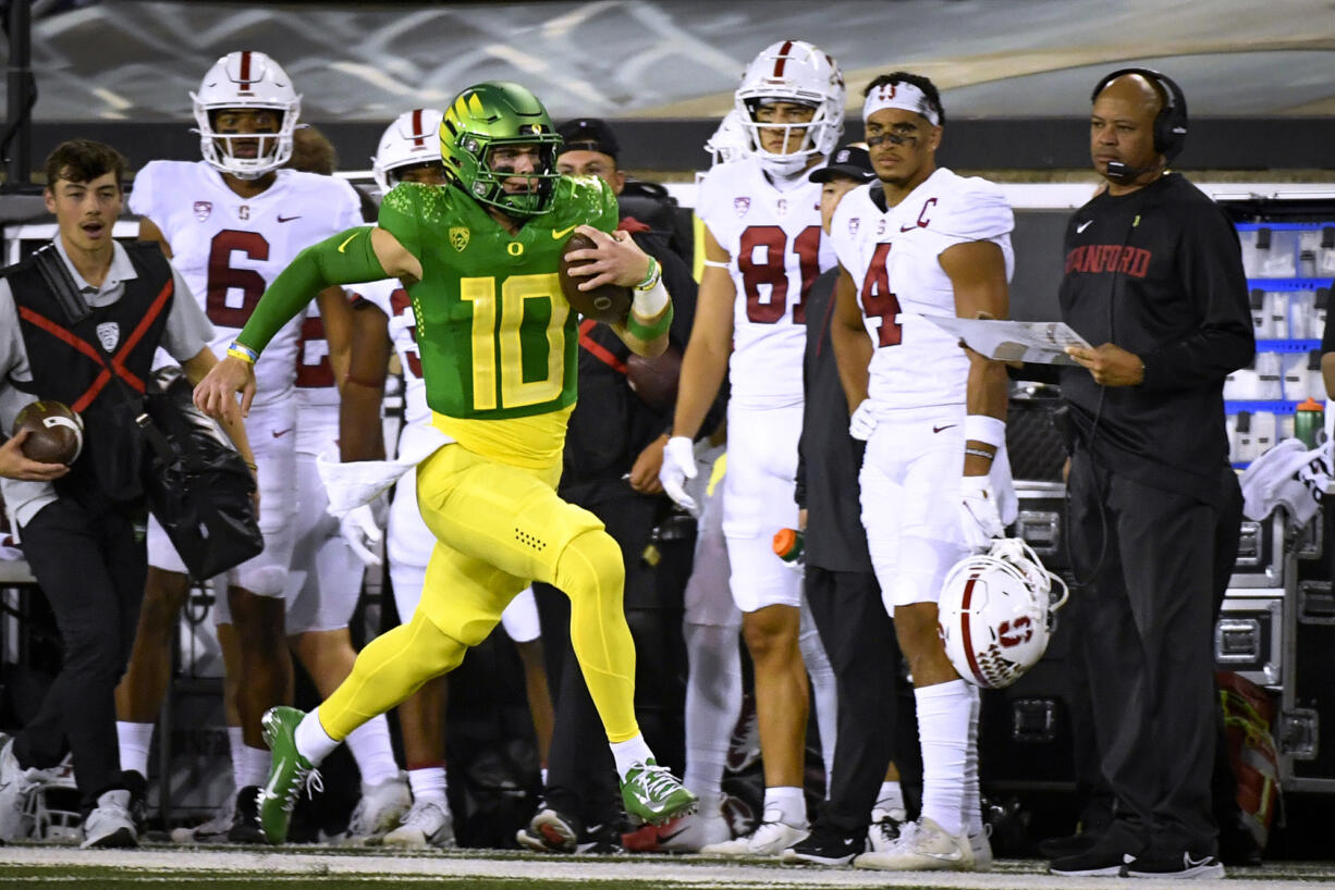 Oregon quarterback Bo Nix (10) runs past Stanford coach David Shaw, right, on a long gain during the first half of an NCAA college football game Saturday, Oct. 1, 2022, in Eugene, Ore.