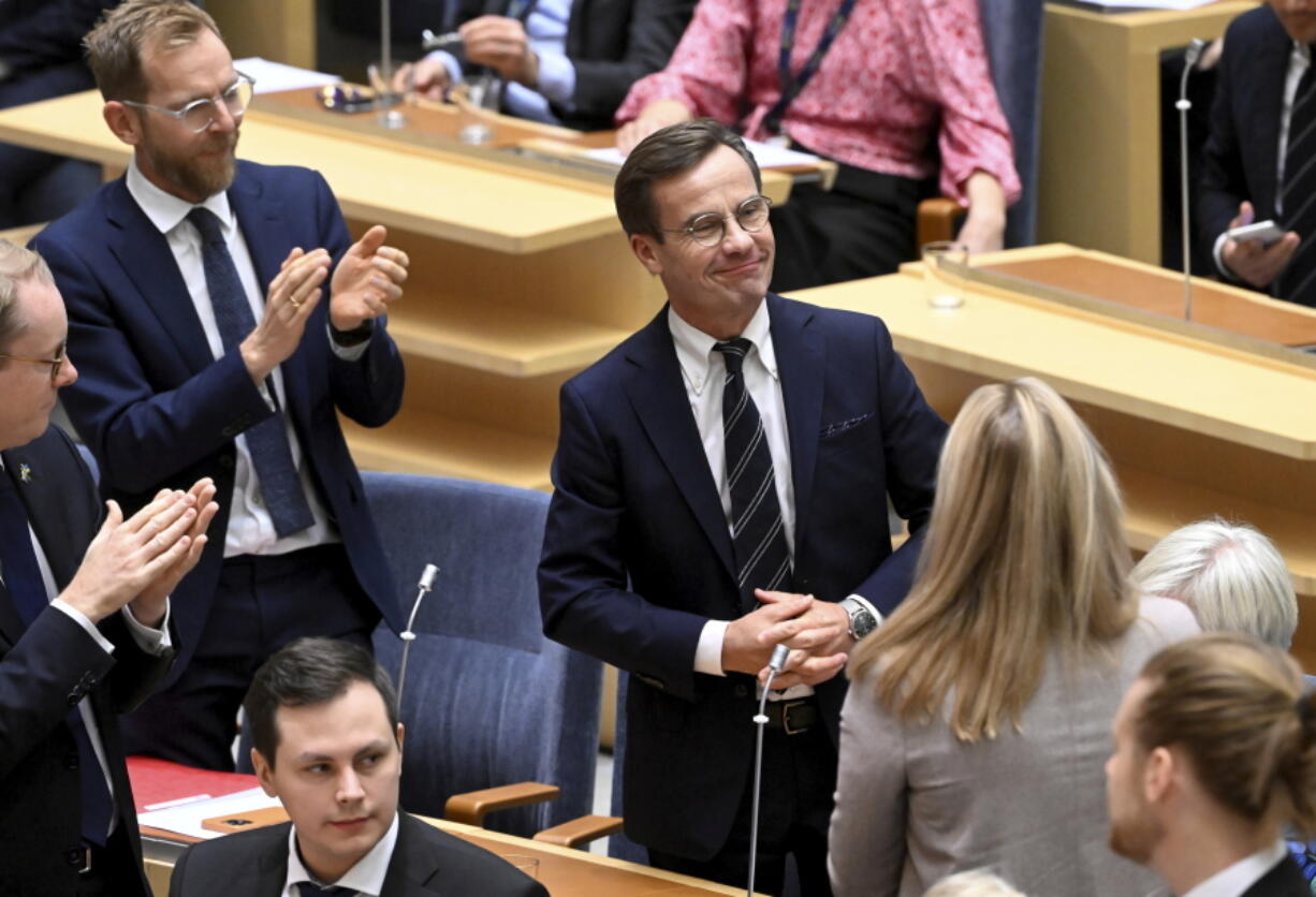 Moderate Party leader Ulf Kristersson, center, smiles after being elected as Sweden's new prime minister at the Parliament in Stockholm, Monday Oct. 17, 2022. The Swedish parliament on Monday elected Kristersson as prime minister at the head of a coalition that is being supported by a once radical far-right party.