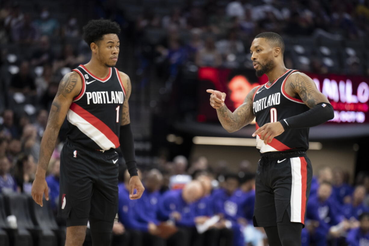 Portland Trail Blazer Damian Lillard (0) explains defensive coverage with teammate Anfernee Simons (1) in the first quarter of an NBA preseason basketball game in Sacramento, Calif., Sunday, Oct. 9, 2022. (AP Photo/Jos?