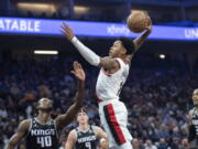 Portland Trail Blazers guard Anfernee Simons (1) goes up for a shot over Sacramento Kings forward Harrison Barnes (40) during the first quarter of an NBA basketball game in Sacramento, Calif., Wednesday, Oct. 19, 2022. (AP Photo/Jos?