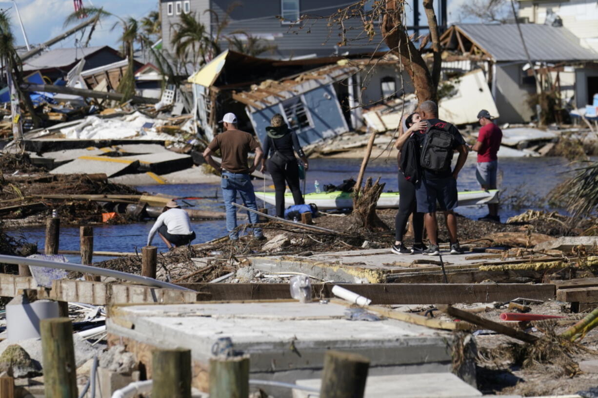 People stand on the destroyed bridge to Pine Island as they view the damage in the aftermath of Hurricane Ian in Matlacha, Fla., Sunday, Oct. 2, 2022. The only bridge to the island is heavily damaged so it can only be reached by boat or air.