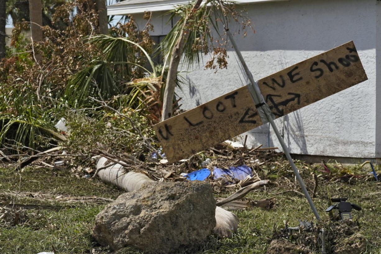 Residents placed a "you loot, we shoot" sign on their their flooded property Tuesday, Oct. 4, 2022, in North Port, Fla. Residents in the area continue cleaning up after Hurricane Ian came ashore along Florida's west coast last week.