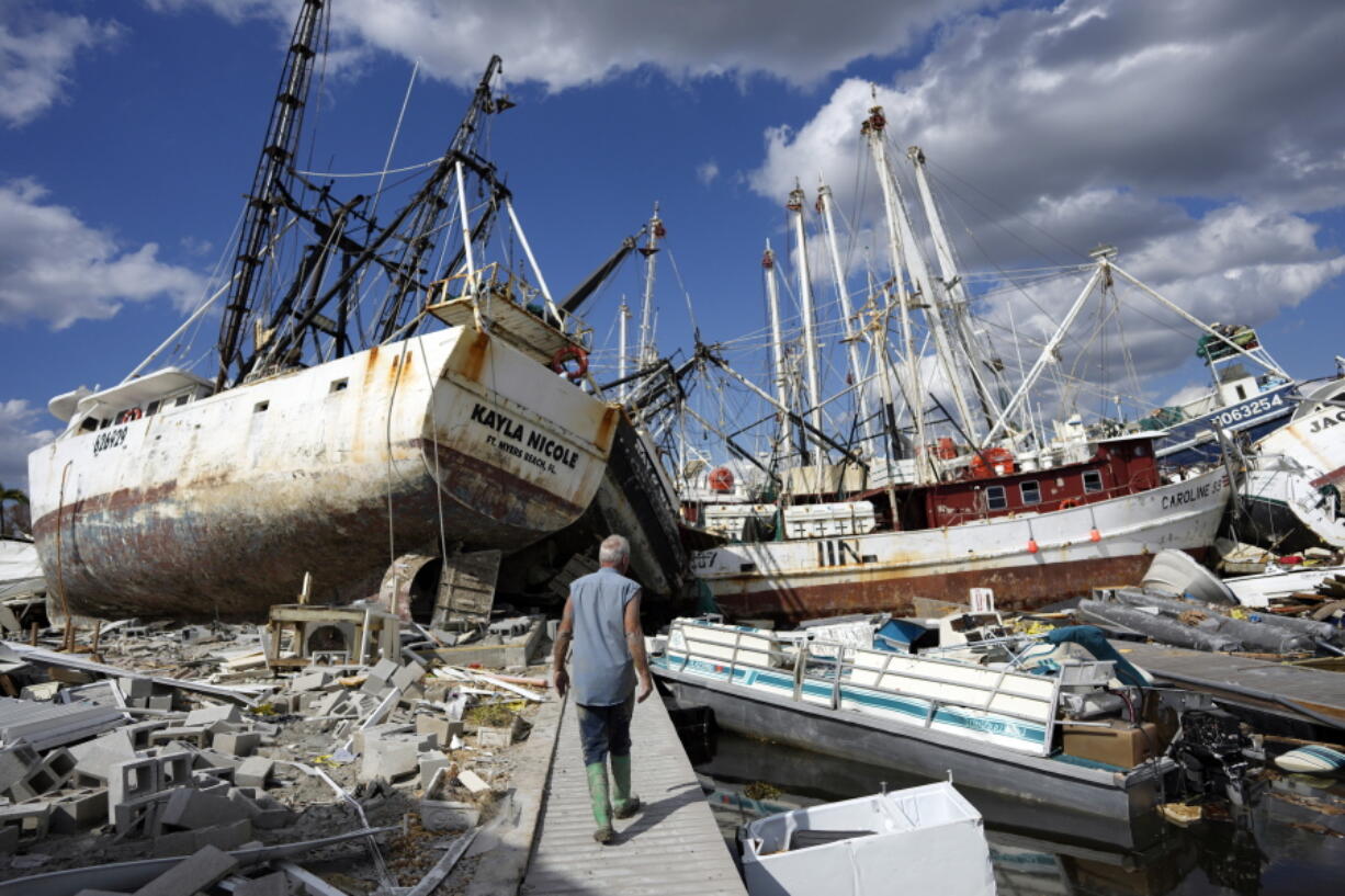 Snowbird Bruce Hickey, 70, walks along the waterfront, now littered with debris including shrimp boats, in the mobile home park where he and his wife Kathy have a winter home, a trailer originally purchased by Kathy's mother in 1979, on San Carlos Island, Fort Myers Beach, Fla., Wednesday, Oct. 5, 2022, one week after the passage of Hurricane Ian.