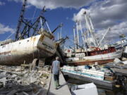 Snowbird Bruce Hickey, 70, walks along the waterfront, now littered with debris including shrimp boats, in the mobile home park where he and his wife Kathy have a winter home, a trailer originally purchased by Kathy's mother in 1979, on San Carlos Island, Fort Myers Beach, Fla., Wednesday, Oct. 5, 2022, one week after the passage of Hurricane Ian.