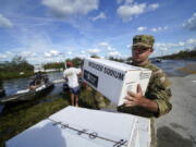 A member of the Florida National Guard helps stack emergency supplies that arrived by boat during flooding along the Peace River in the aftermath of Hurricane Ian in Arcadia, Fla., Monday, Oct. 3, 2022.