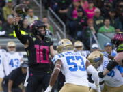 Oregon's Bo Nix, left, throws down field ahead UCLA's Darius Muawai during the first half in an NCAA college football game Saturday, Oct. 22, 2022, in Eugene, Ore.