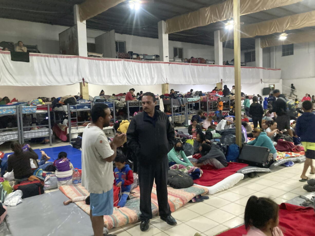 Gustavo Banda, center right -- pastor of Templo Embajadores de Jesus, the largest migrant shelter in Tijuana, Mexico -- speaks with migrants Thursday at the overflowing facility. The Biden administration's policy shift on Venezuelan migrants may pose an enormous challenge to overstretched Mexican shelters.