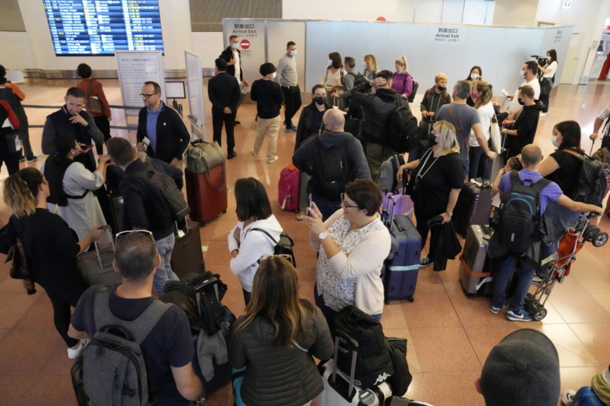 Foreign travelers gather upon arrival at the Haneda International Airport Tuesday, Oct. 11, 2022, in Tokyo. Japan's strict border restrictions are eased, allowing tourists to easily enter for the first time since the start of the COVID-19 pandemic. Independent tourists are again welcomed, not just those traveling with authorized groups.