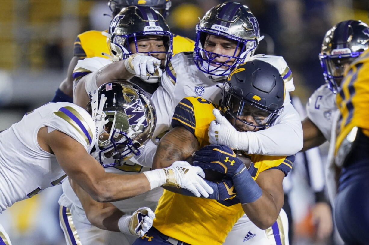 California running back DeCarlos Brooks (25) is tackled by Washington safety Alex Cook and defensive linemen Tuli Letuligasenoa and Bralen Trice Washington, from left, during the first half of an NCAA college football game in Berkeley, Calif., Saturday, Oct. 22, 2022. (AP Photo/Godofredo A.