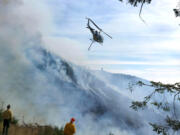 A helicopter drops water on the Nakia Creek Fire in east Clark County on Oct. 12, 2022.