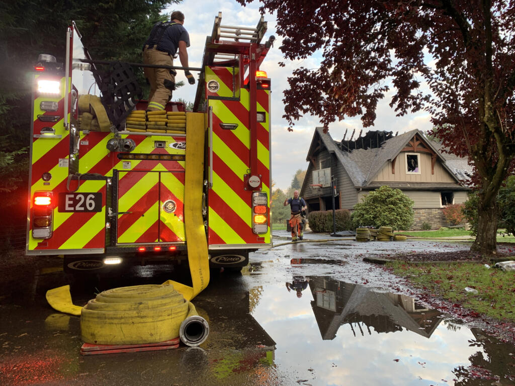 Firefighter/paramedic Geoff Gutridge reloads a hose used to battle a house fire Thursday morning south of Battle Ground.