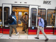 Joseph Fowler, right, is one of roughly 65,000 Clark County workers who commute to Portland. But unlike most of them, he rides public transportation.  At top, a C-Tran bus stops at the Fisher's Landing Transit Center before taking commuters to the Parkrose/Sumner transit center in Portland so they can board a MAX light rail train.