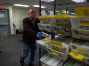 Inspection board worker Frank Lesick pushes verified, counted ballots into a safe after being processed at the county elections office Monday.