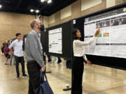 Joy Young, right, highlights a piece of her research on axonopathy to a conference attendee on Oct. 11 at the 2022 Biomedical Engineering Society Conference in San Antonio, Texas.