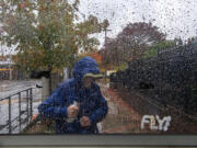 Raindrops hang on the side of a bus shelter as a passenger bundles up against the wind and rain Friday afternoon in downtown Vancouver. Stormy weather blanketed the area as an atmospheric river barreled into Washington and Oregon.