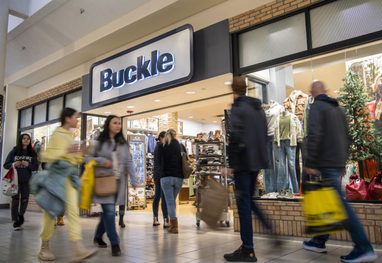 Black Friday shoppers pass in front of Buckle on Friday at Vancouver Mall. Early-morning doorbuster deals are largely no more. Instead, shoppers came in a steady stream throughout the day. At top, shoppers wait in line outside Bath & Body Works at the mall.