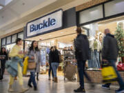 Black Friday shoppers pass in front of Buckle on Friday at Vancouver Mall. Early-morning doorbuster deals are largely no more. Instead, shoppers came in a steady stream throughout the day. At top, shoppers wait in line outside Bath & Body Works at the mall.