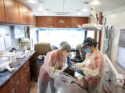 Gloria Sanchez Keeth, Clinic manager with Medical Teams International, and dentist Thien-Y Hoang work on a patient inside the Mobile Dental Clinic during a community wellness event at Chemeketa Community College in Salem, Ore. on Saturday, Oct.