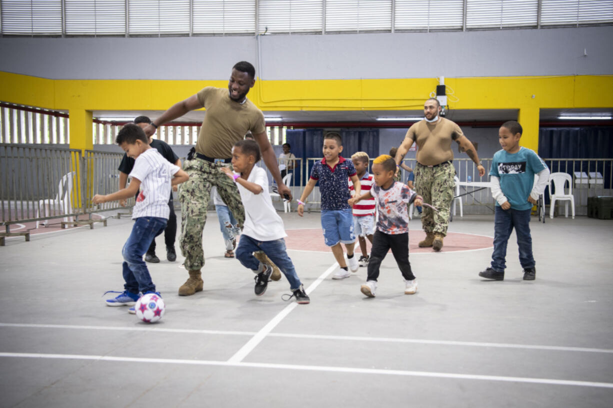 Hospital Corpsman Third Class Joshua Soske, from La Center, and Hospital Corpsman Third Class Lou-Shane Daley, from St. Catherine, Jamaica, play soccer with children at the Sports Coliseum of Combat and Gymnastics in Cartagena, Colombia. (U.S.