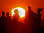 A blazing sun silhouettes visitors to Signal Hill after another hot day across Southern California, on Sept. 1.