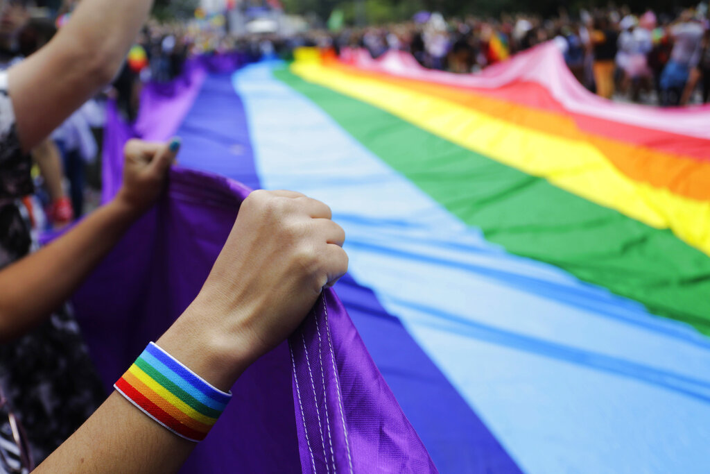 FILE - In this Sunday, June 3, 2018 file photo, revelers at the annual gay pride parade hold up a giant rainbow flag in Sao Paulo, Brazil. Rainbow flags will be allowed in stadiums at the 2022 World Cup as Qatar, with a strictly conservative religious code and anti-LGBTQ laws, accepts complying with FIFA regulations promoting tolerance and inclusion at matches.