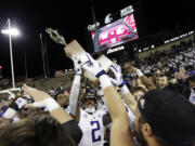 Washington players celebrate with the Apple Cup Trophy after their 51-33 win against Washington State in an NCAA college football game, Saturday, Nov. 26, 2022, in Pullman, Wash.