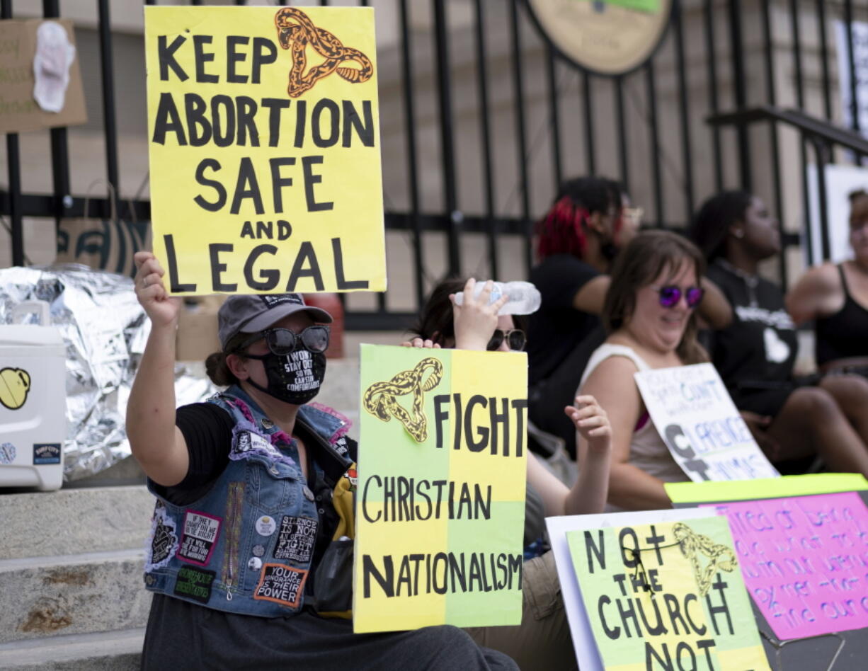 FILE - A small group, including Stephanie Batchelor, left, sits on the steps of the Georgia state Capitol protesting the overturning of Roe v. Wade on June 26, 2022. A judge overturned Georgia's ban on abortion starting around six weeks into a pregnancy, ruling Tuesday, Nov. 15, 2022 that it violated the U.S. Constitution and U.S. Supreme Court precedent when it was enacted.