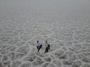 State of Utah Department of Natural Resources geologists Paul Inkenbrandt, left, and Jeremiah Bernau walk along the Bonneville Salt Flats on Aug. 29, 2022, near Wendover, Utah. The glistening white salt of the world famous area is shrinking near the Utah-Nevada line.