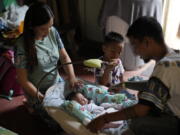 Hyancinth Charm Garing, left, and husband Jeremy, right, play with their month-old daughter inside their home at a new community for victims of super Typhoon Haiyan in Tacloban, central Philippines on Sunday Oct. 23, 2022. Garing and his family settled at a relocation site three years ago after their village was wiped out when the super typhoon struck in 2013, killing six family members and his year-old daughter.