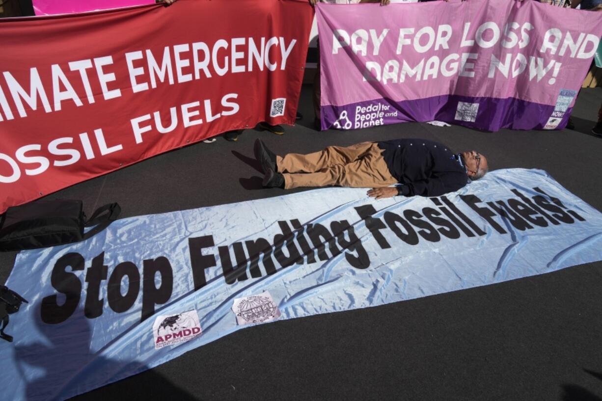 FILE - A demonstrator lies on the ground while participating in a protest against fossil fuels at the COP27 U.N. Climate Summit, Nov. 11, 2022, in Sharm el-Sheikh, Egypt. As the U.N. climate talks in Egypt near the half-way point, negotiators are working hard to draft deals on a wide range of issues they'll put to ministers next week in the hope of getting a substantial result by the end.