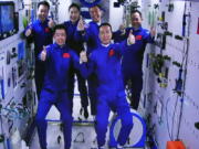 In this photo released by Xinhua News Agency, an image captured off a screen at the Jiuquan Satellite Launch Center in northwest China shows the Shenzhou-15 and Shenzhou-14 crew taking a group picture with their thumbs up after a historic gathering in space on Wednesday, Nov. 30, 2022. Three Chinese astronauts docked early Wednesday with their country's space station, where they will overlap for several days with the three-member crew already onboard and expand the facility to its maximum size.