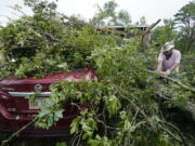 FILE - Span McGinty uses his chain saw to cut fallen tree limbs from a tornado-damaged vehicle at his brother's house in Yazoo County, Miss., on May 3, 2021. 90% of counties in the United States experienced a weather-related disaster between 2011-2021, according to a report published on Wednesday, Nov. 16, 2022. Over 300 million people -- 93% of the country's population -- live in those counties. (AP Photo/Rogelio V.