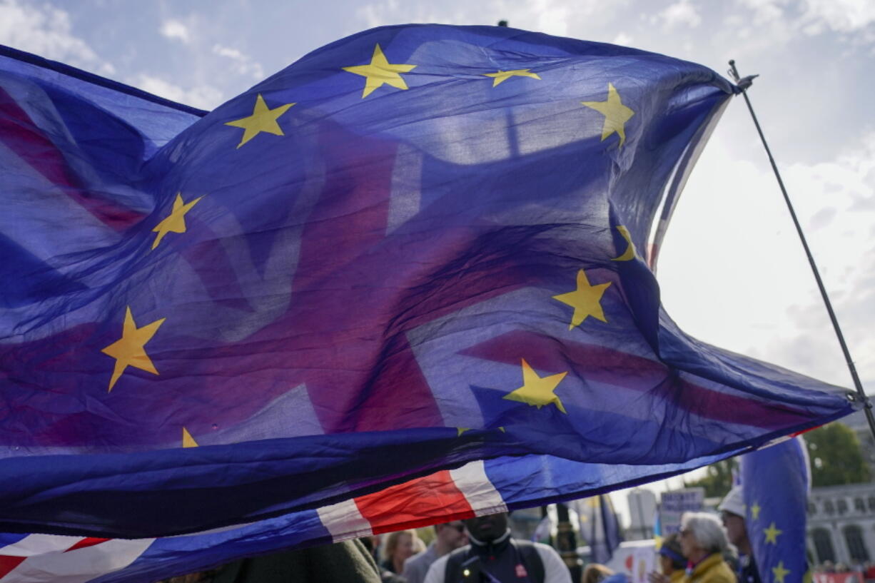 FILE - A Union flag waves behind a European Union flag, outside the Houses of Parliament, in London, Wednesday, Oct. 19, 2022. The British government on Sunday, Nov. 20, 2022 denied a report it is seeking a "Swiss-style" relationship with the European Union that would remove many of the economic barriers erected by Brexit -- even as it tries to repair ties with the bloc after years of acrimony.