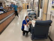 FILE - A nurse talks to a patient in the emergency room at Salem Hospital in Salem, Ore., on Aug. 20, 2021. Oregonians will vote Tuesday, Nov. 8, 2022, on a slate of measures including one that would add a permit and in-person firearms training class for new gun buyers and another that would make Oregon the first state to mandate health care as a human right.