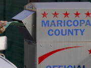 FILE - A voter casts their ballot at a secure ballot drop box at the Maricopa County Tabulation and Election Center in Phoenix, Nov. 1, 2022. The Justice Department will send monitors to 24 states in an effort to ensure compliance with federal voting rights laws in Tuesday's elections. The 64 jurisdictions where federal monitors are being sent include Maricopa County, Arizona, where there have been reports of people watching ballot boxes, sometimes armed or wearing ballistic vests.