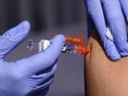 FILE - A patient is given a flu vaccine at the L.A. Care and Blue Shield of California Promise Health Plans' Community Resource Center where they were offering members and the public free flu and COVID-19 vaccines Friday, Oct. 28, 2022, in Lynwood, Calif. As Americans head into the late 2022 holiday season, a rapidly intensifying flu season is straining hospitals already overburdened with patients sick from other respiratory infections. (AP Photo/Mark J.