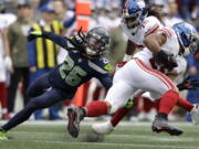 New York Giants running back Saquon Barkley, right, runs against Seattle Seahawks safety Ryan Neal during the first half of an NFL football game in Seattle, Sunday, Oct. 30, 2022.