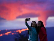 Ingrid Yang, left, and Kelly Bruno, both of San Diego, take a photo in front of lava erupting from Hawaii's Mauna Loa volcano Wednesday, Nov. 30, 2022, near Hilo, Hawaii.