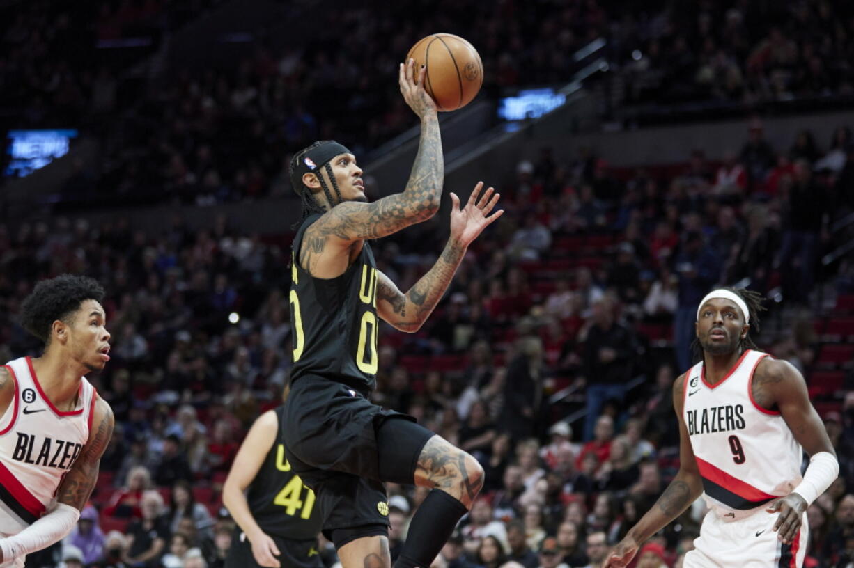 Utah Jazz guard Jordan Clarkson, center, shoots between Portland Trail Blazers guard Anfernee Simons, left, and forward Jerami Grant during the second half of an NBA basketball game in Portland, Ore., Saturday, Nov. 19, 2022.