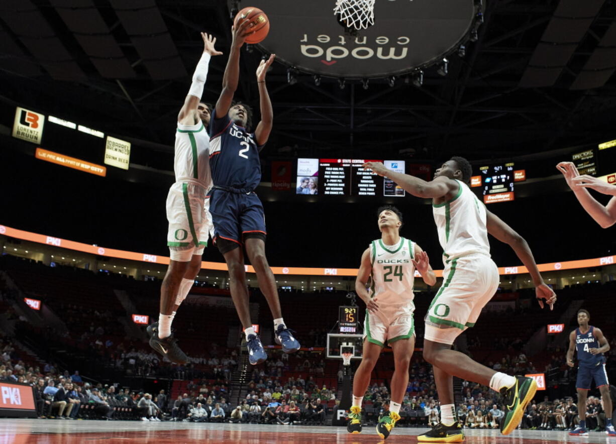 Connecticut guard Tristen Newton (2) shoots between Oregon guard Rivaldo Soares, left, guard Brady Parris (24) and center N'Faly Dante during the second half of an NCAA college basketball game in the Phil Knight Invitational tournament in Portland, Ore., Thursday, Nov. 24, 2022.