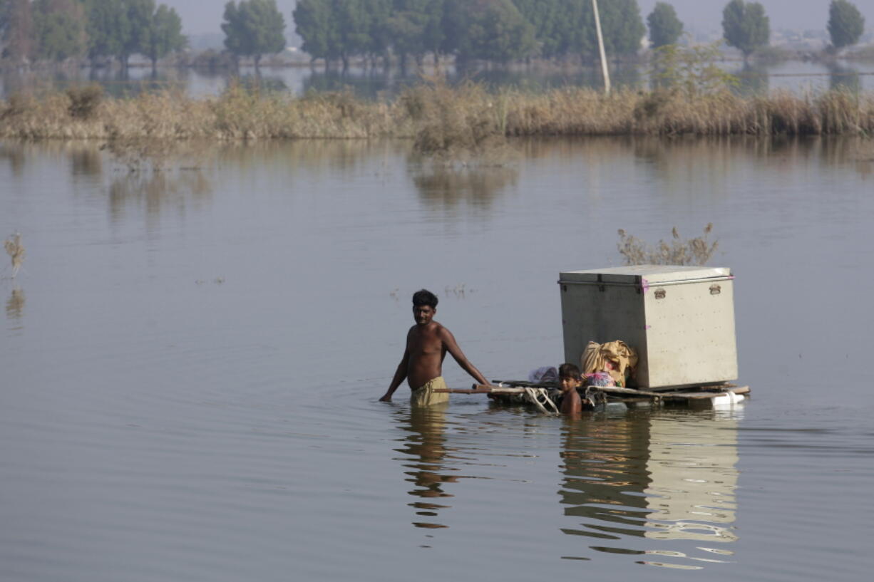 Villagers retrieve belongings while they wade through a flooded area, in Qambar Shahdadkot, in Sindh province, Pakistan.