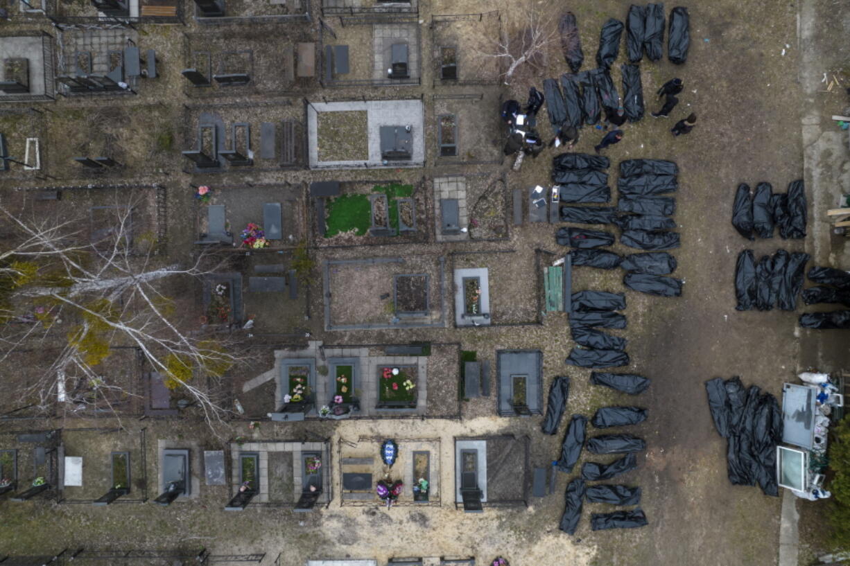 FILE - Policemen work to identify civilians who were killed during the Russian occupation in Bucha, Ukraine, on the outskirts of Kyiv, before sending the bodies to the morgue, Wednesday, April 6, 2022. Russian soldiers in intercepted phone conversations called their sweeps of Bucha and other towns "zachistka" - cleansing. They hunted people on lists prepared by their intelligence services and went door to door to identify and neutralize potential threats.