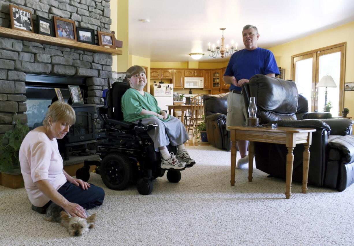 This undated photo shows Terry Horgan with his parents in the family's Montour Falls, N.Y., home. Horgan, a 27-year-old who had Duchenne muscular dystrophy, died last month, Oct. 2022,  according to Cure Rare Disease, a Connecticut-based nonprofit founded by his brother, Rich, to try and save him. Although it's still unclear what killed him, his death is raising questions about the experiment and the overall prospect of what one ethicist calls designer genetic therapies.