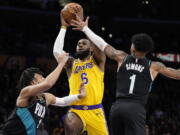 Los Angeles Lakers forward LeBron James, center, shoots as Portland Trail Blazers forward Trendon Watford, left, and guard Anfernee Simons defends during the first half of an NBA basketball game Wednesday, Nov. 30, 2022, in Los Angeles. (AP Photo/Mark J.