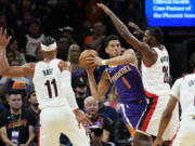 Phoenix Suns guard Devin Booker (1) looks to pass under pressure from Portland Trail Blazers forward Justise Winslow (26) during the first half of an NBA basketball game, Saturday, Nov. 5, 2022, in Phoenix.