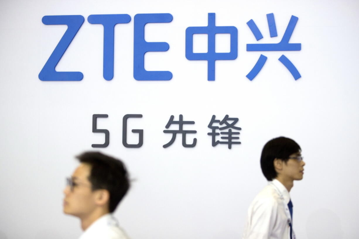 FILE - In this Sept. 26, 2018 file photo, visitors walk past a display from Chinese technology firm ZTE at the PT Expo in Beijing. The U.S. is banning the sale of communications equipment made by Chinese companies Huawei and ZTE and restricting the use of some China-made video surveillance systems, citing an "unacceptable risk" to national security. The 5-member Federal Communications Commission said Friday, Nov. 25, 2022 it has voted unanimously to adopt new rules that will block the importation or sale of certain technology products that pose security risks.