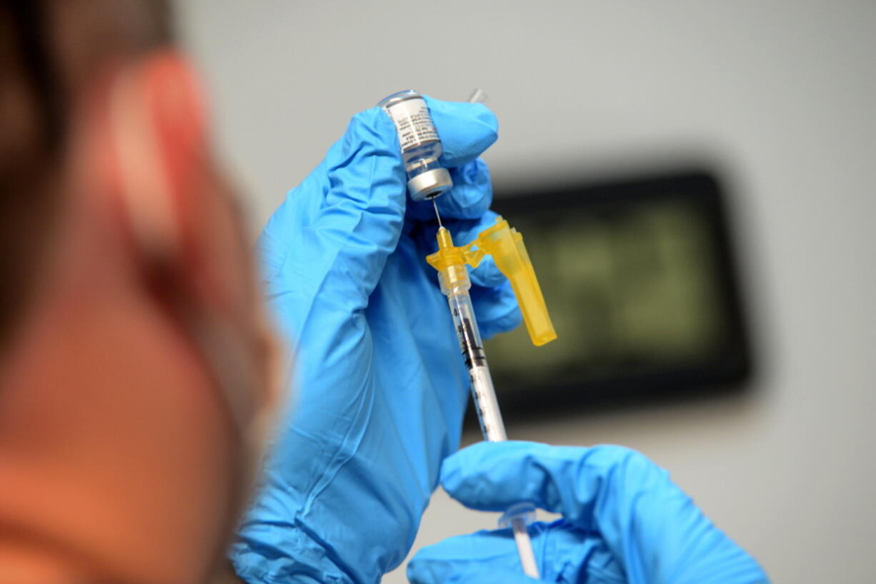 FILE - Ryan Dutton, an EMT from Rescue Inc., prepares shots of the Pfizer COVID-19 booster vaccine during a vaccine clinic held by Rescue Inc. at Leland & Gray Middle and High School, in Townshend, Vt., on Tuesday, Sept. 20, 2022. The updated COVID-19 boosters aren't an exact match to the newest omicron mutants but Pfizer says lab tests suggest its shot may offer some cross-protection.