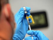 FILE - Ryan Dutton, an EMT from Rescue Inc., prepares shots of the Pfizer COVID-19 booster vaccine during a vaccine clinic held by Rescue Inc. at Leland & Gray Middle and High School, in Townshend, Vt., on Tuesday, Sept. 20, 2022. The updated COVID-19 boosters aren't an exact match to the newest omicron mutants but Pfizer says lab tests suggest its shot may offer some cross-protection.