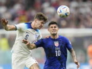 England's John Stones vies for the ball with Christian Pulisic of the United States, right, during the World Cup group B soccer match between England and The United States, at the Al Bayt Stadium in Al Khor , Qatar, Friday, Nov. 25, 2022.